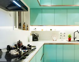Elegant kitchen by interior designers in Udupi, featuring turquoise cabinets, white countertops, and a sleek modern design